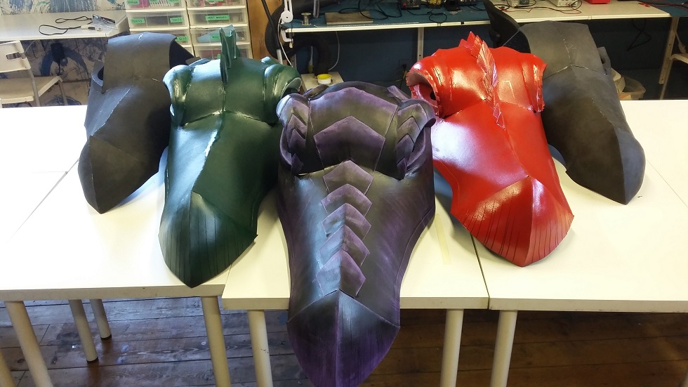 five foam dragon heads at varying stages of completeness