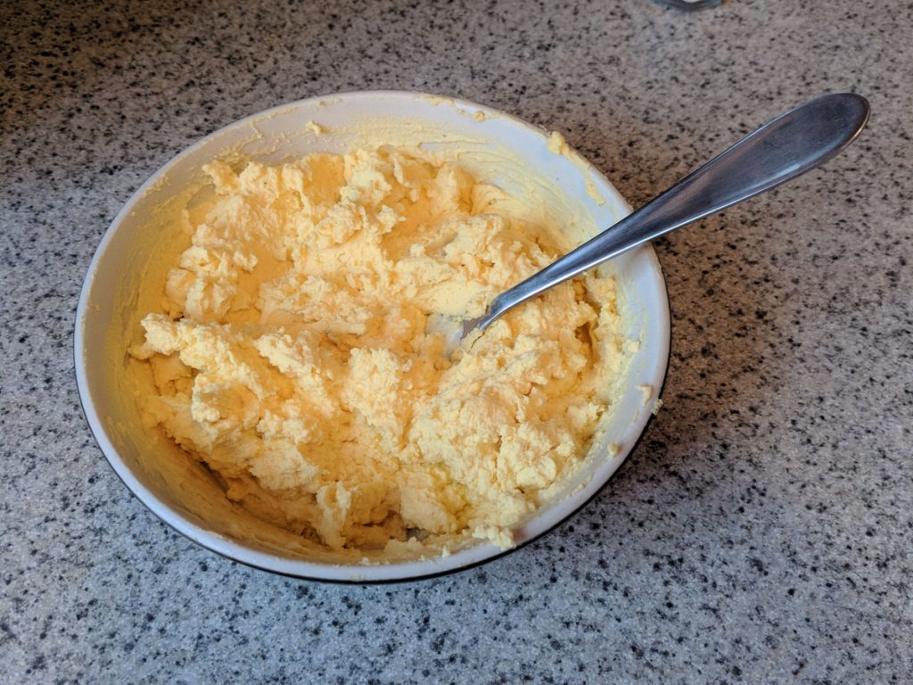 a white bowl with a fork sticking out of mashed yellow egg yolks